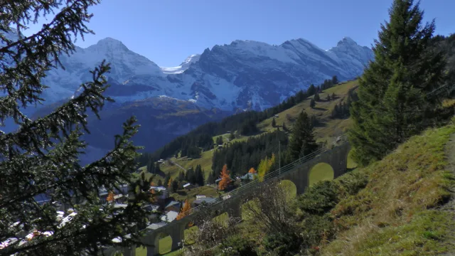 Blick vom Panoramaweg über die Häuser von Mürren auf die verschneite Bergkette dahinter