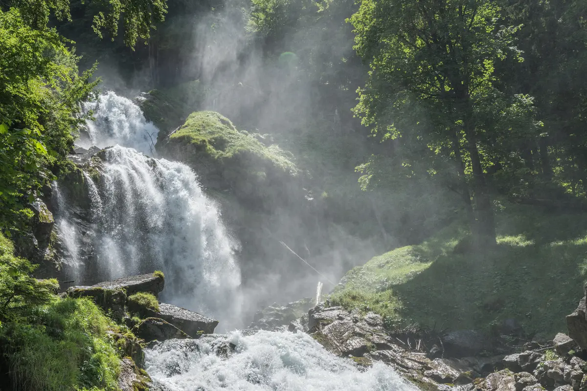 Die Giessbachfälle stürzen in mehreren Stufen über bemooste Felsen durch den Wald, Gischt in der Luft