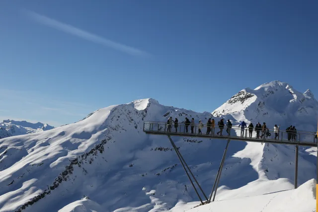 Menschen auf dem Stahlsteg des First Cliff Walk, der im Winter aus der verschneiten Bergflanke ragt