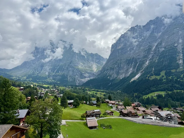 Das Dorf Grindelwald im Talboden unter der Wand des Wetterhorns, Wolken um die Gipfel
