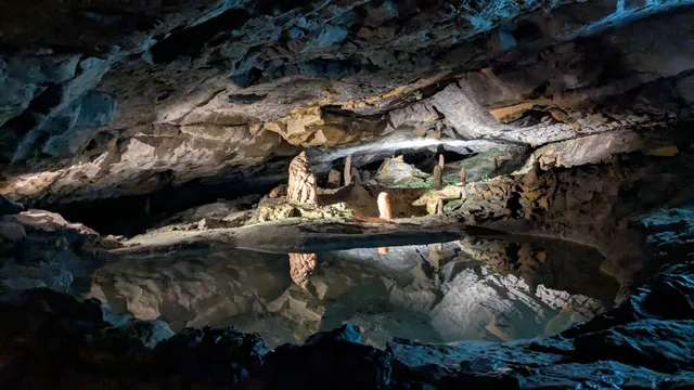 Still pool inside the St Beatus Caves reflecting a stalagmite and the cave roof