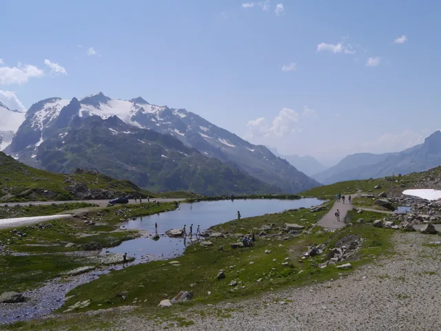 Bergsee auf der Passhöhe des Sustenpasses, am Ufer Wandernde, dahinter vergletscherte Gipfel
