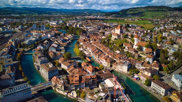 Luftbild der Thuner Altstadt mit der Aare, dem Schloss auf dem Hügel und roten Ziegeldächern
